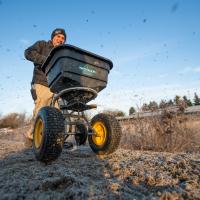 man spreading flower seed with broadcast seeder