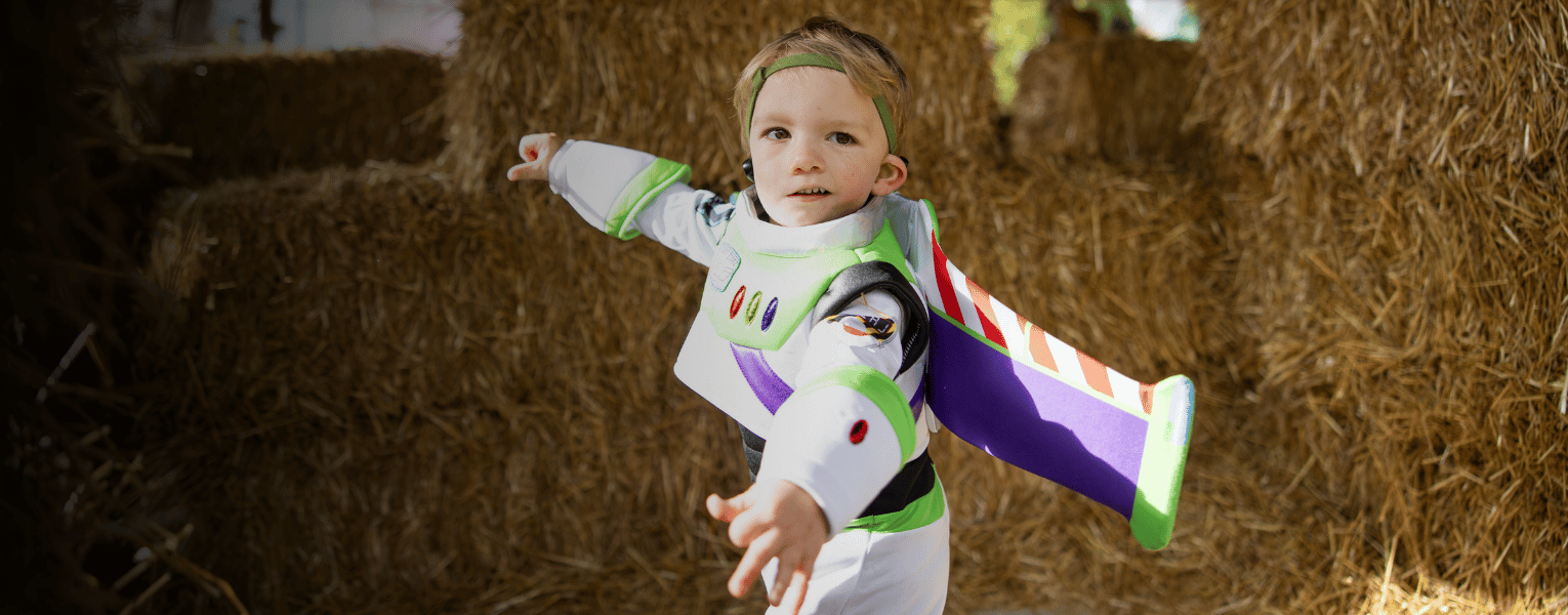 child in costume in front of hay bales