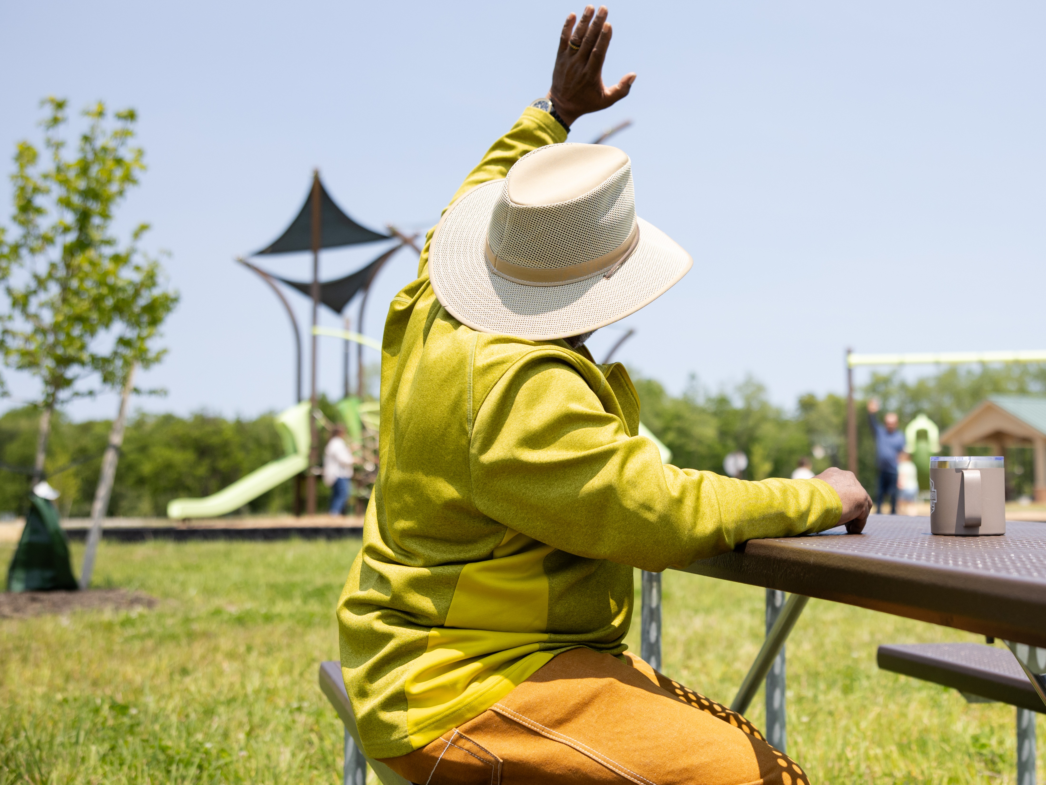 man waving to campground guests in background