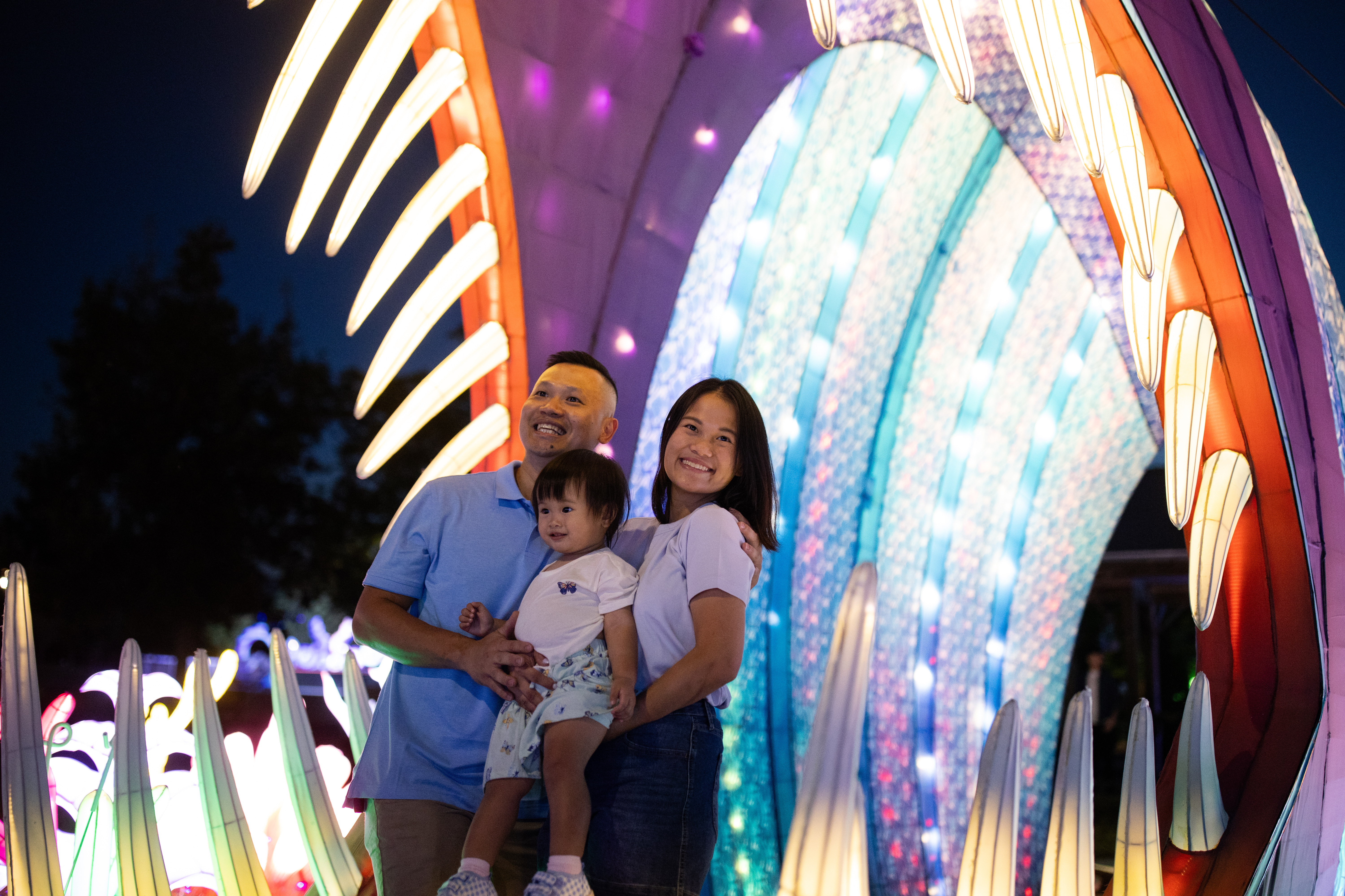 family smiling in front of large lantern