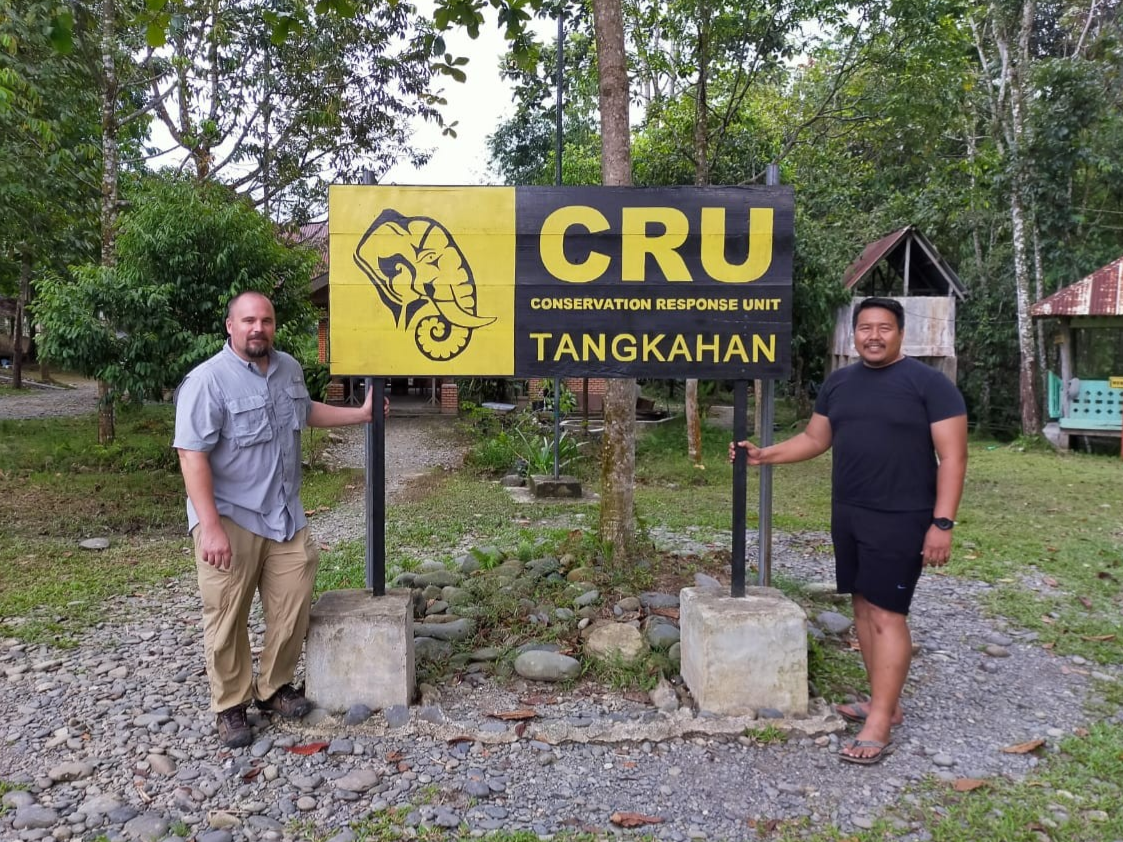 two men posing by sign