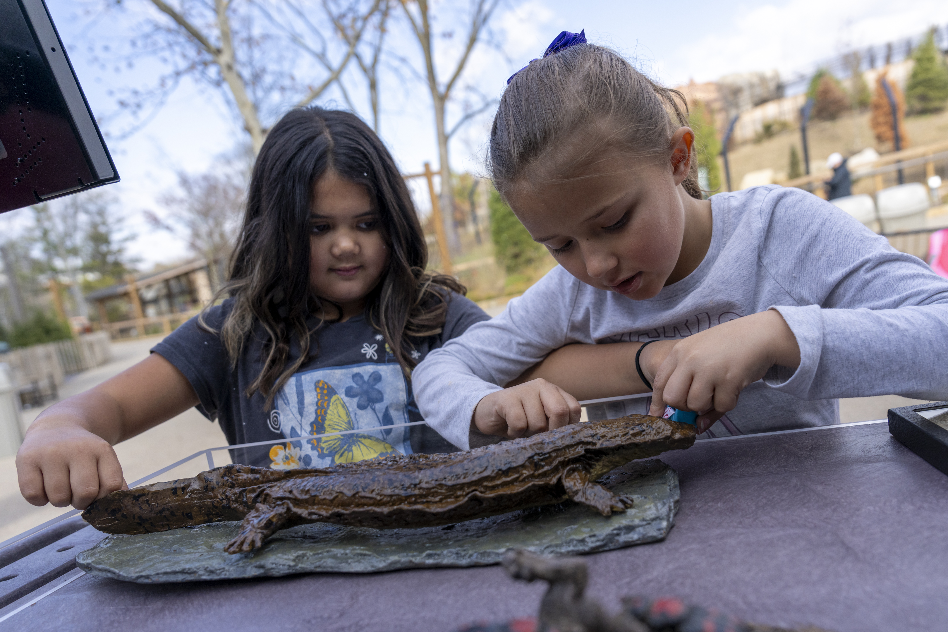 children measuring animal statue