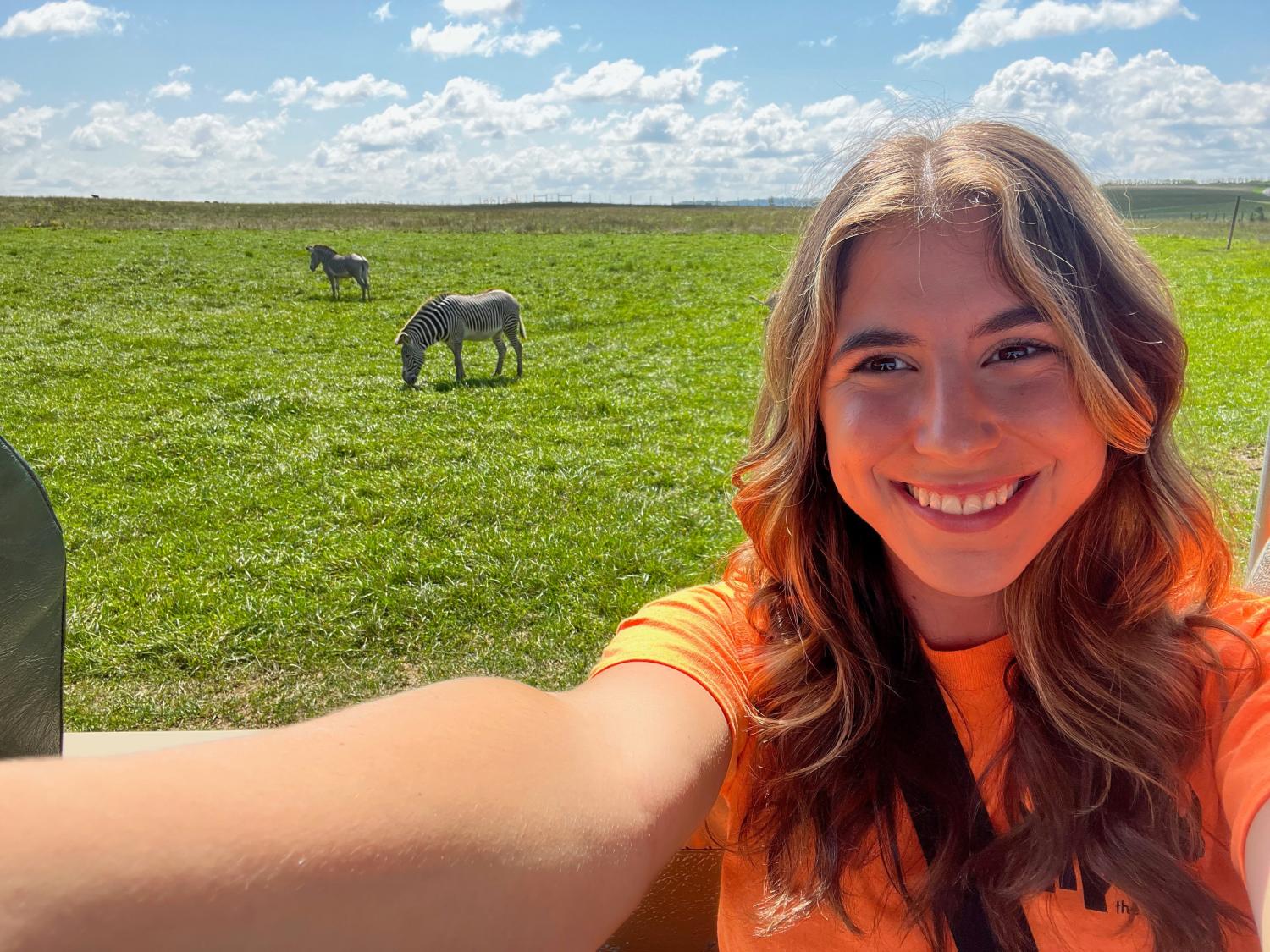 girl in orange shirt with zebras in background