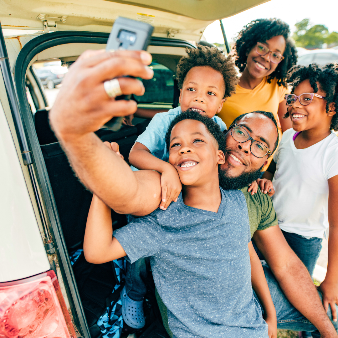 family taking selfie near their car