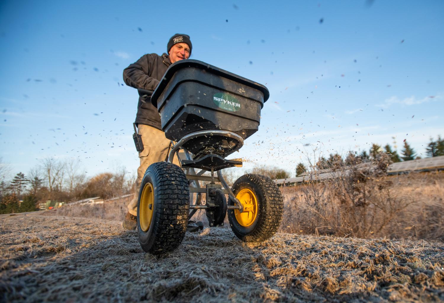 Columbus Zoo team member spreading seed using the broadcast method