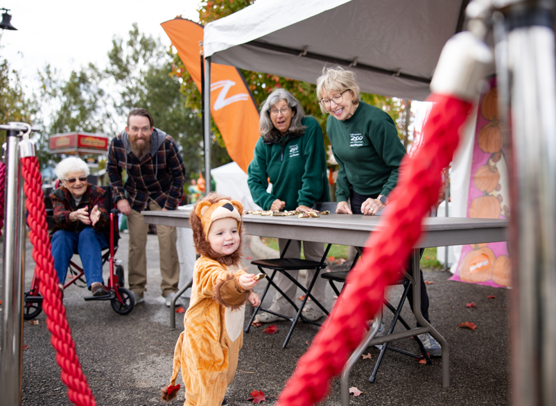 child holding candy with zoo employees in background, smiling