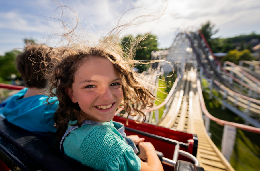 child smiling at camera while riding roller coaster at the columbus zoo