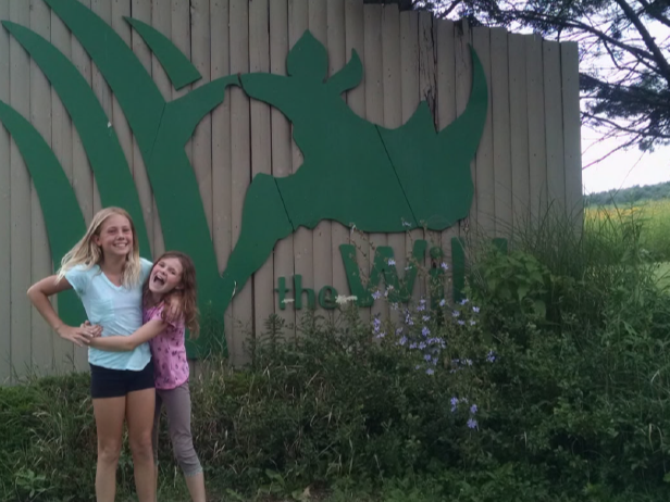 two girls posing for photo near large sign that says The Wilds