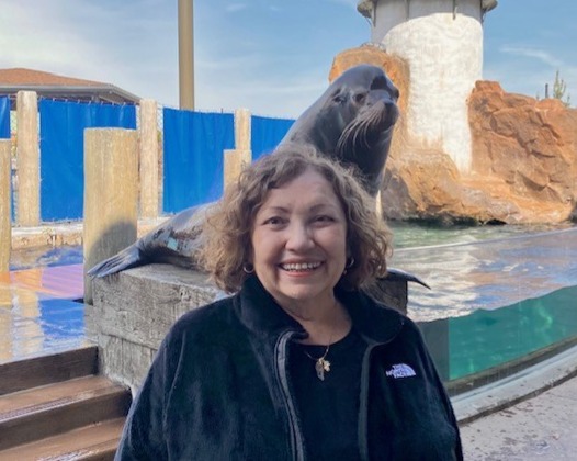 woman posing for photo with sea lion in background
