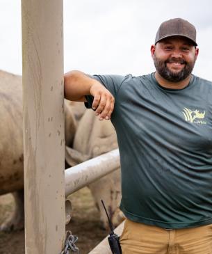 man posing next to rhino