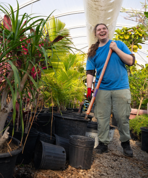 team member working in greenery and smiling