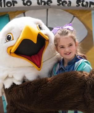 child posing with zoo mascot