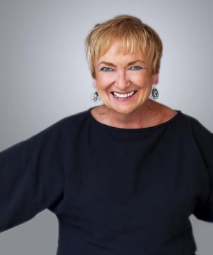 Charlene wearing black shirt with arms outstretched smiling at camera