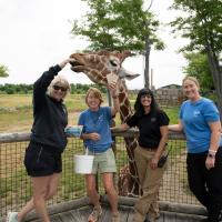 Zoo staff members posing with giraffe