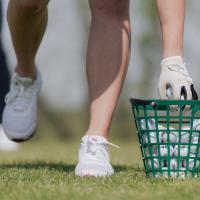 person picking ball up out of green basket