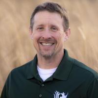 man posing for photo with field behind him