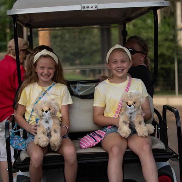 two girls on back of golf cart