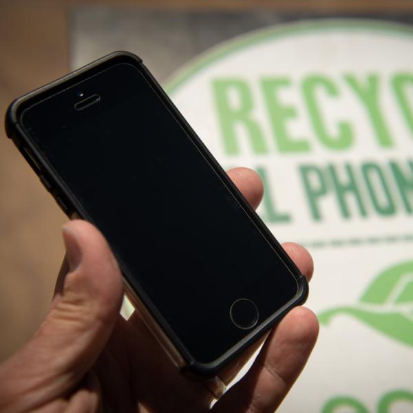 cell phone held in front of recycling sign