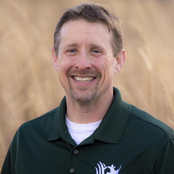 man posing for photo with field behind him