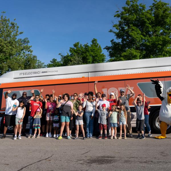 group of people smiling and posing in front of orange bus