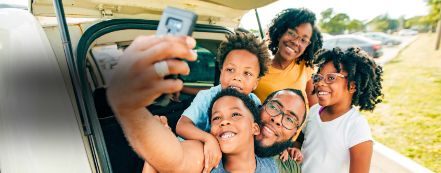 family taking selfie near car
